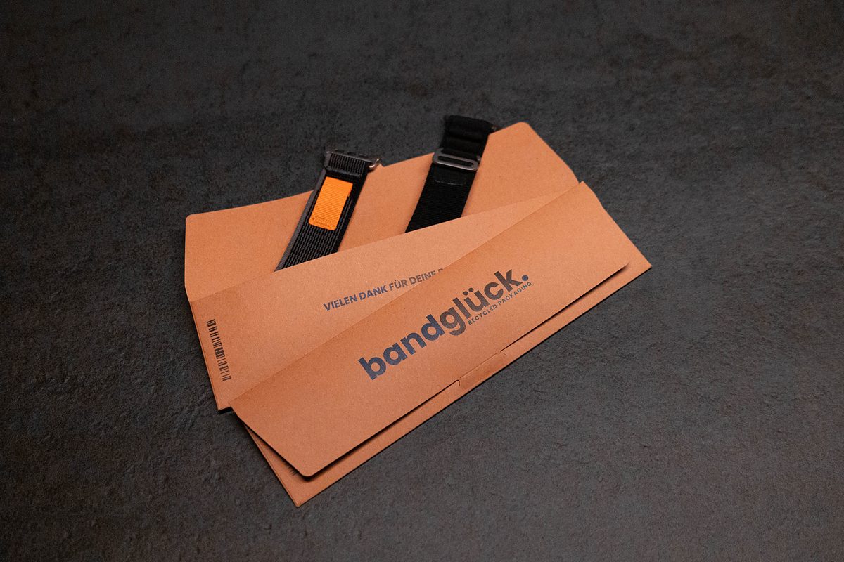 Bandglück-Versandhülle aus recyceltem Karton mit zwei Armbändern